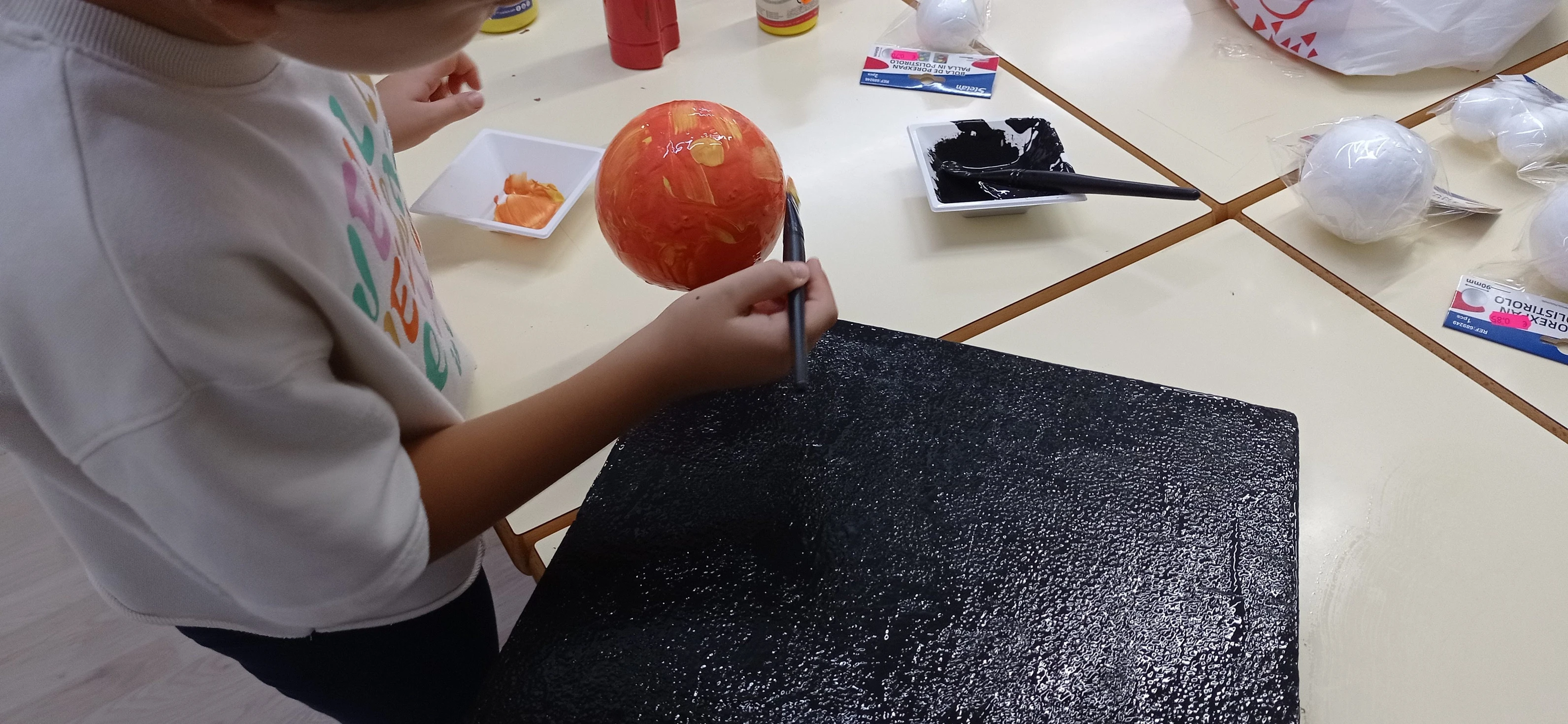 Niño pintando una maqueta del sol