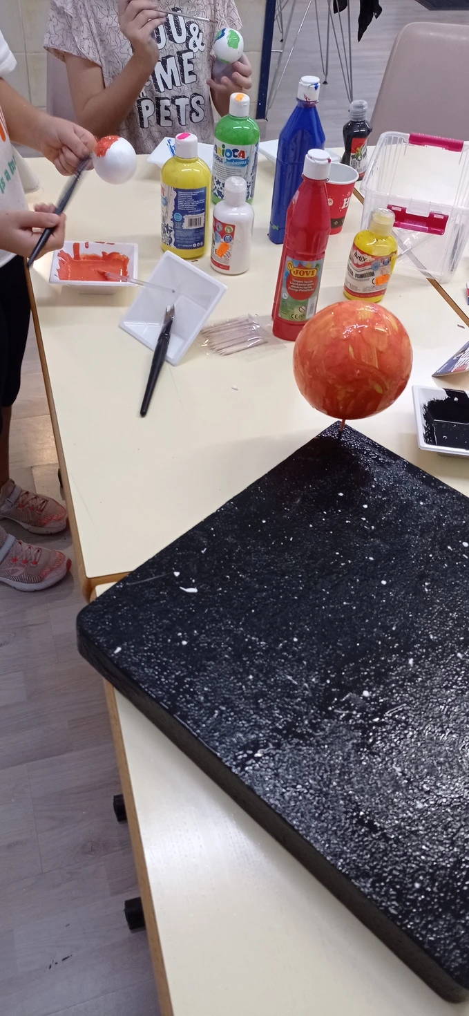 Maqueta del sol sobre una plancha pintada con estrellas